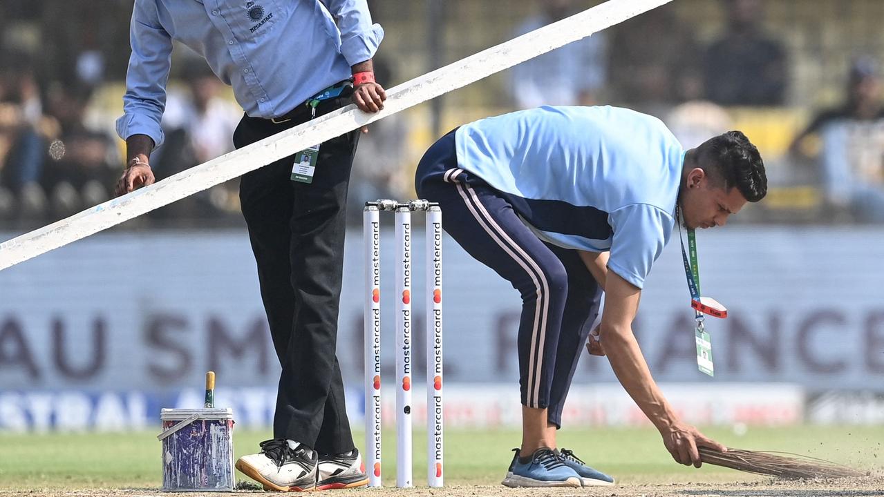 Ground staff members clean the pitch in Indore.