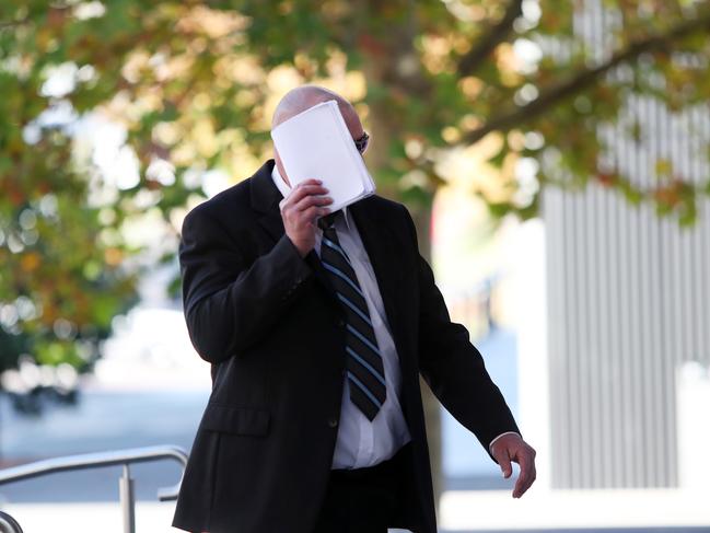 Joshua Monger hides his face as he arrives at Wyong Local Court. Picture: Sue Graham