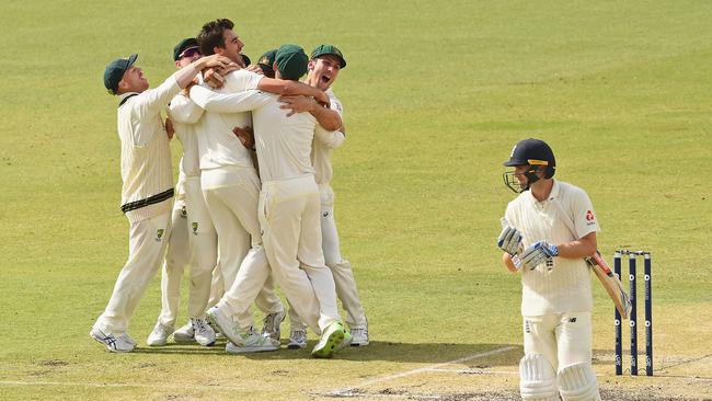 Teammates mob Pat Cummins after he dismissed England’s Chris Woakes during the third Ashes Test in Perth. Picture: Getty