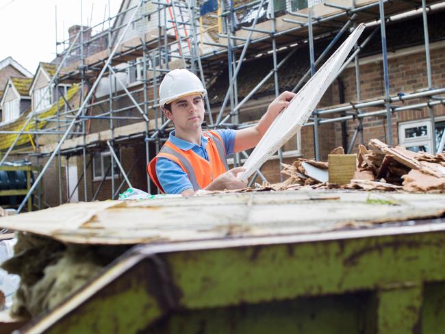 Builder On Site Putting Waste Into Rubbish Skip