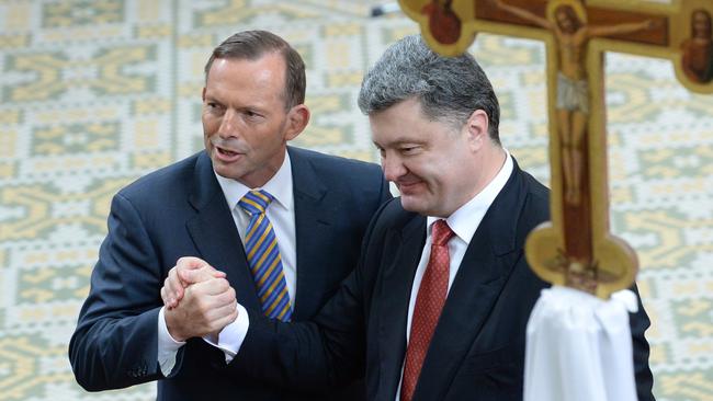 Tony Abbott and Petro Poroshenko shake hands during a church service in Melbourne.