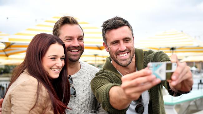 The Bachelorette contestants James Trethewie and Luke Mcleod pose for a selfie with a fan at the Wharf Bar in Manly. (AAP Image/Joel Carrett)