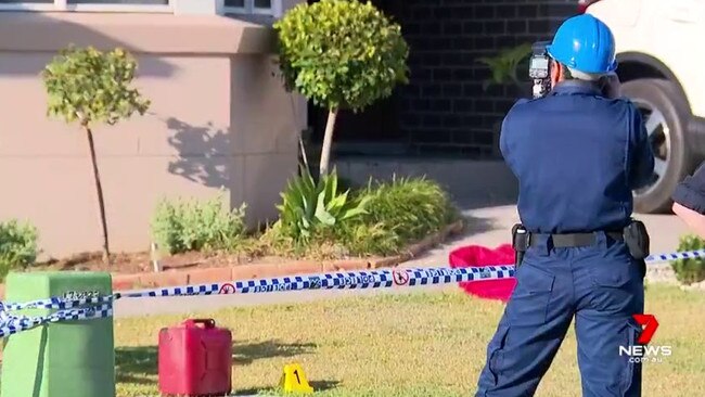 Police photograph the scene, including a jerry can on the lawn, on Sunday morning. Picture: 7 News