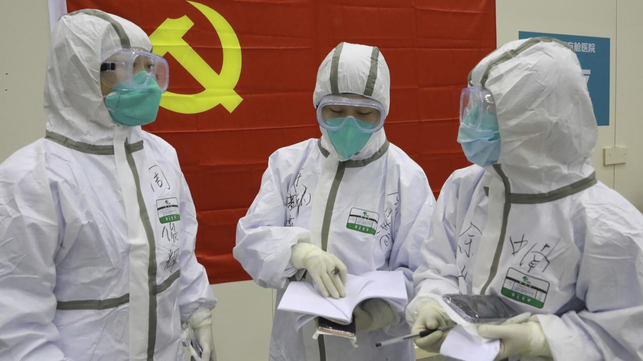 Medical workers discuss patients' treatment near a Communist Party flag at the ‘Wuhan Living Room’ temporary hospital in Wuhan. Picture: Gao Xiang/Xinhua via AP.