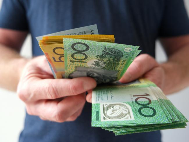 A man counting Australian dollar bills. A picture that describes buying, paying, handing out money, or showing money. Australian cash money generic