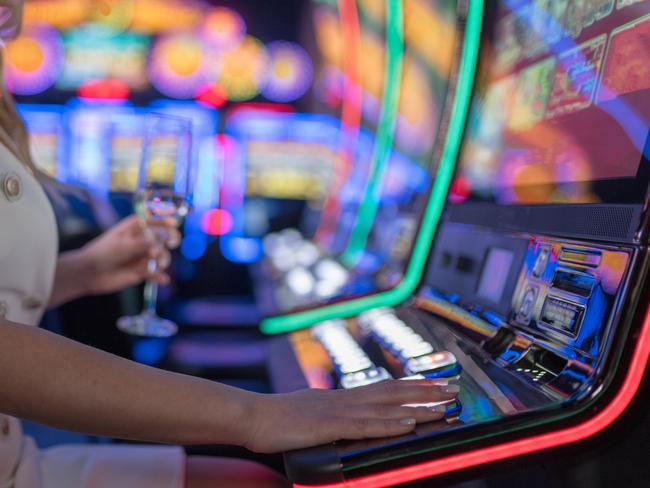 beautiful girl drinking wine alone at casino poker machine pokies istock generic