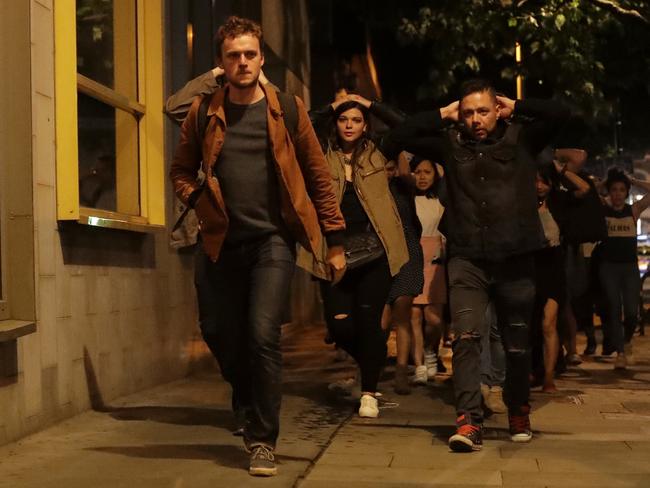 People with their hands on their heads about 10 minutes after midnight as they leave from inside a police cordon after an attack in London. Picture: AP