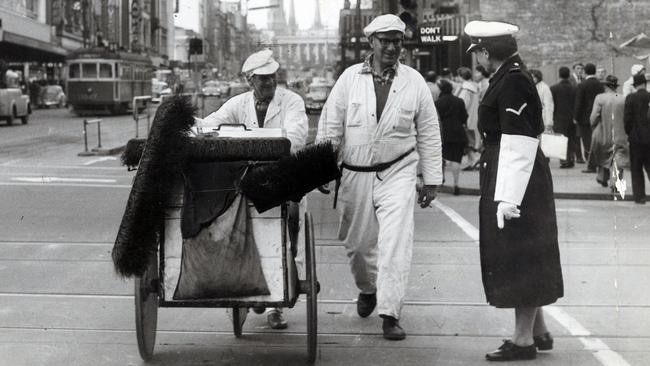 Street cleaners on the corner of Swanston and Bourke streets chat with Constable Marjory Bowden in 1961.