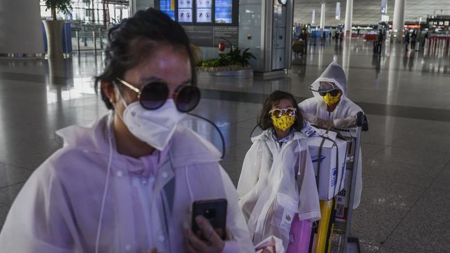 BEIJING, CHINA - MARCH 24: A Chinese family wear protective masks, sunglasses and raincoats after arriving on a flight at Beijing Capital International Airport. (Photo by Kevin Frayer/Getty Images)