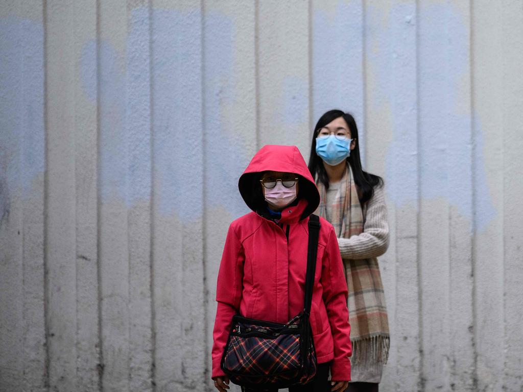 Pedestrians wear face masks as they prepare to cross a road in Hong Kong, which became the second place outside mainland China to report a death from the disease. Picture: Anthony Wallace / AFP.