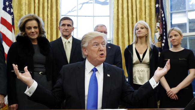 President Donald Trump pauses before signing one of three executive actions in the Oval Office. Kellyanne Conway is second from the right. Picture: AP