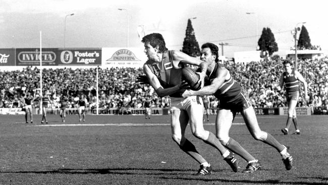 Robbie Flower is tackled by Phil Cronan at the Western Oval.