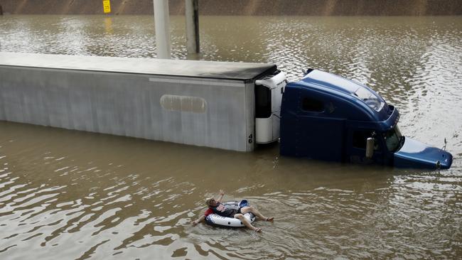 A man floats past a truck submerged on a freeway flooded by Tropical Storm Harvey on Sunday. Picture: Charlie Riedel/AP