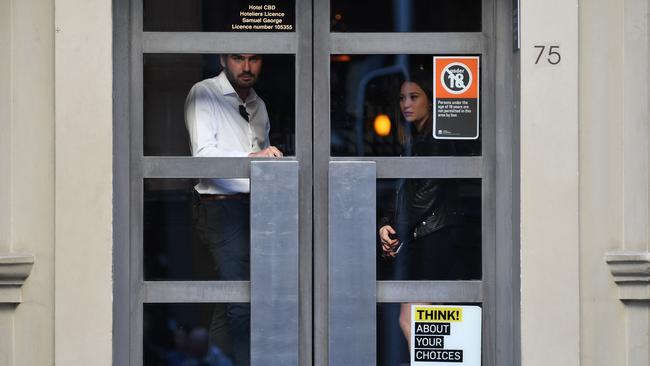 People huddle inside a nearby hotel as police swarm. Picture: AFP