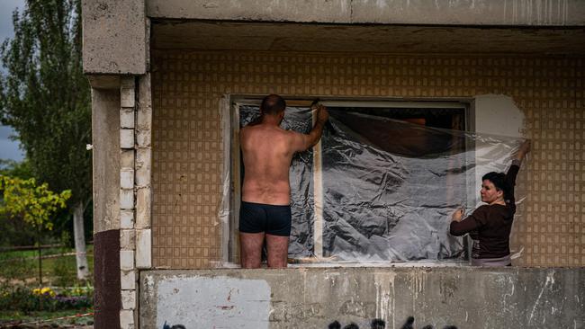 Local residents cover a broken window with plastic film, a broken window following a missile strike in Dnipro. Picture: AFP