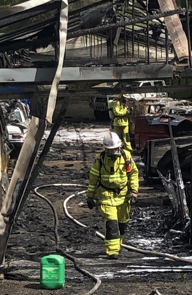 A firefighter in the remains of a storage shed containing a number of rare and collectable cars destroyed by the fire at Ingleside. Picture: Jim O'Rourke