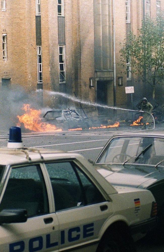 A bomb expert douses the flames outside the police complex.