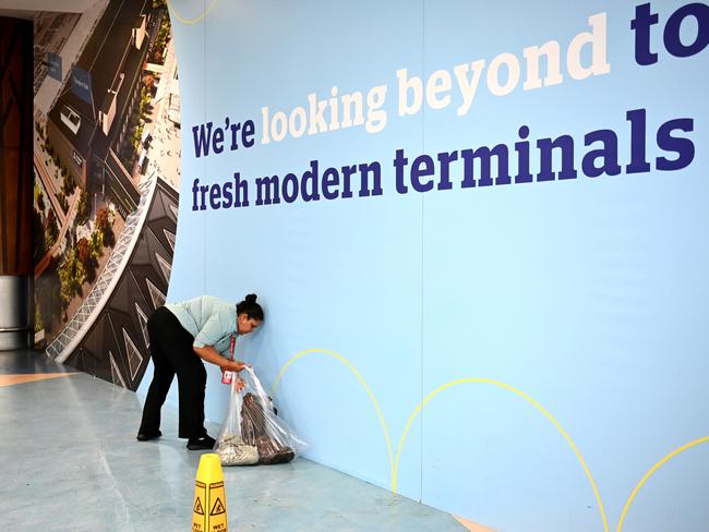 A cleaner picks up towels from the ground at Auckland Airport after Auckland was hit with a historic amount of torrential rainfall, causing severe flooding. Picture: Getty Images