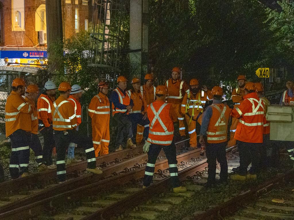 Rail workers surveying the train that hit powerlines near Homebush station. Picture: Thomas Lisson