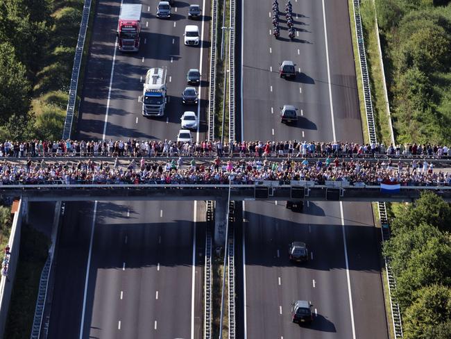 People on a bridge watch as the convoy of hearses pass by. AFP PHOTO/ANP/JERRY LAMPEN