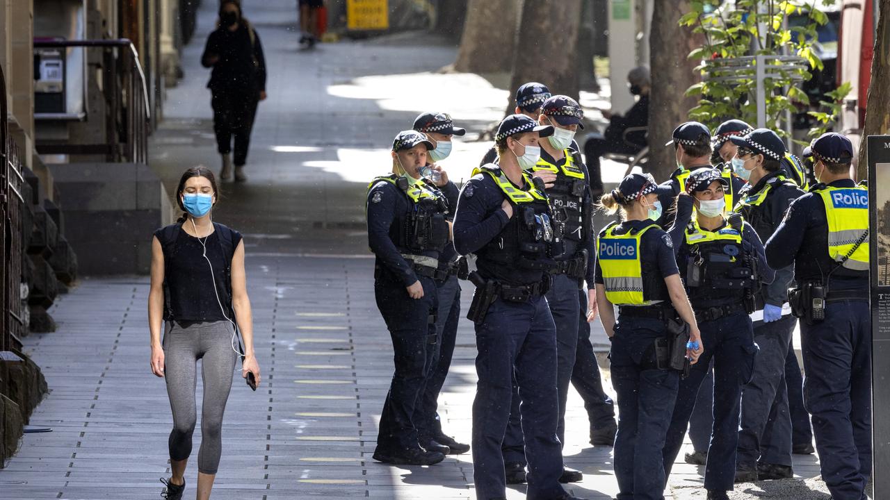 A woman walks along Collins St as police officers patrol the CBD during Melbourne's sixth Covid lockdown. Picture: NCA NewsWire / David Geraghty