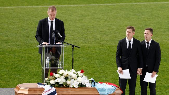Adam speaking as Scott and Joel Selwood look on during Troy’s funeral. (Photo by Michael Willson/AFL Photos)