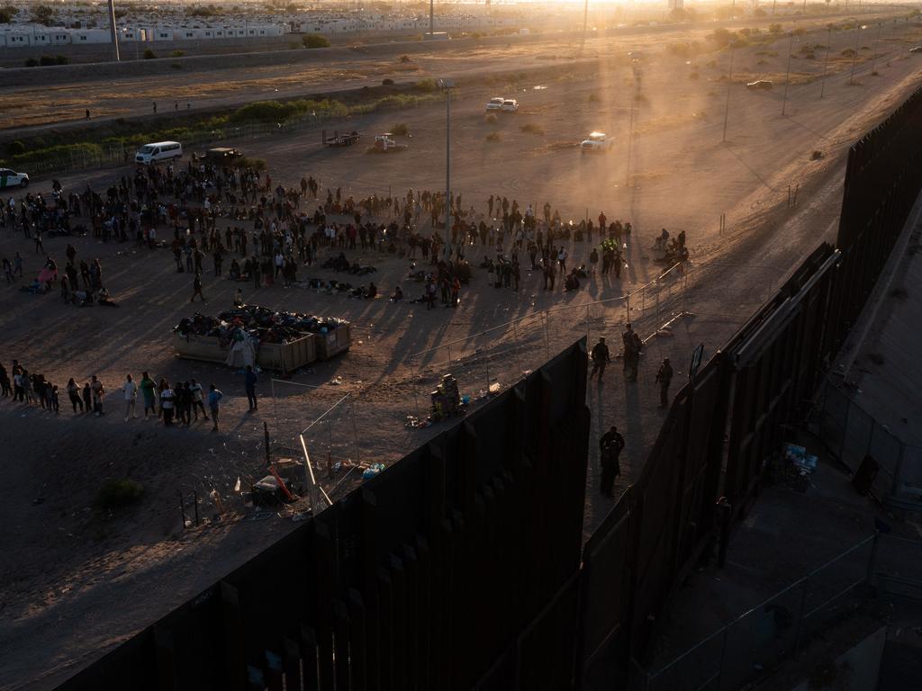 In this aerial picture taken on May 11, 2023 migrants line up to walk to board vans after waiting along the border wall to surrender to US Customs and Border Protection agents for immigration and asylum claim processing. Picture: Patrick T. Fallon/AFP