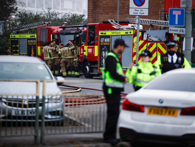 Police officers and firefighters near the scene where the fire broke out. Picture: AFP