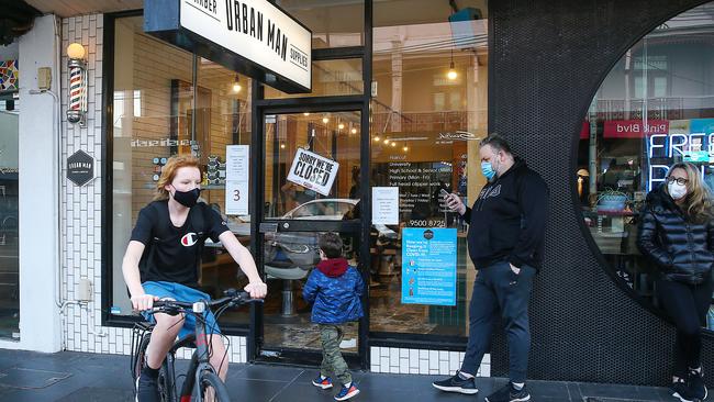 A man waits in line for a haircut at Urban Man Barber in Glenferrie Rd before hairdressers are shut down under stage four restrictions. Picture: Ian Currie/NCA NewsWire.