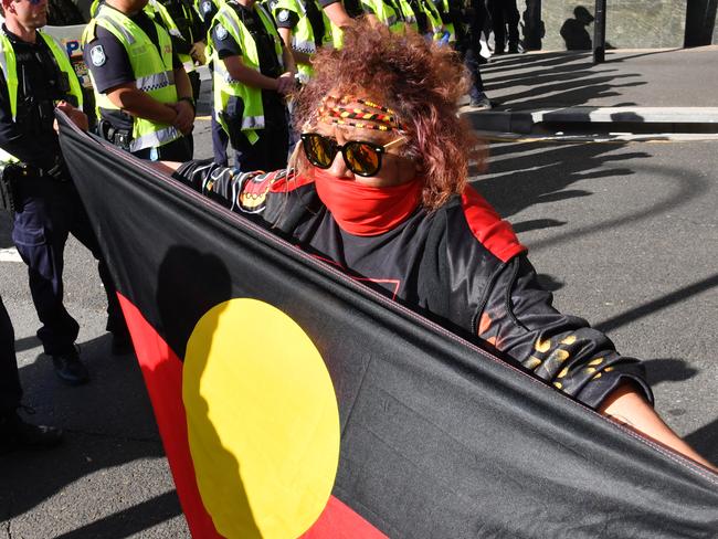 Police and a Black Lives Matter protestor (centre) carrying an Aboriginal flag are seen during a protest outside the Roma Street Magistrates Court in Brisbane, Wednesday, June 17, 2020. (AAP Image/Darren England) NO ARCHIVING