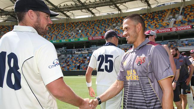 Queensland captain Usman Khawaja (right) shakes hands with Victoria’s Jon Holland after Queensland won their Sheffield Shield match by eight wickets on Thursday. Picture: AAP