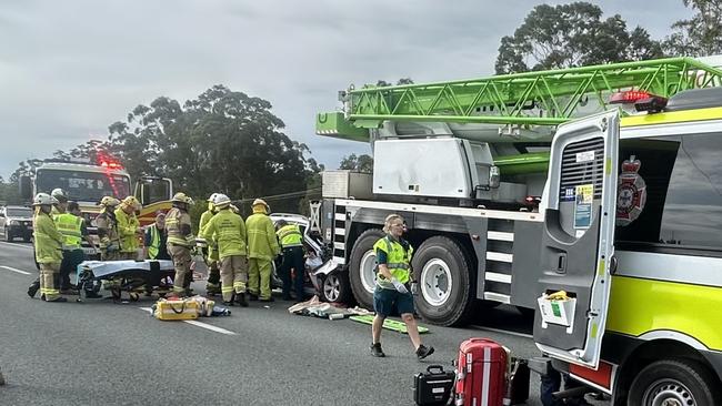 Emergency crews work at the crash scene behind the crane truck on the Bruce Highway near Cooroy.