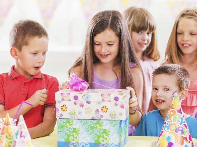 Children's birthday party. Little girl is opening her presents.