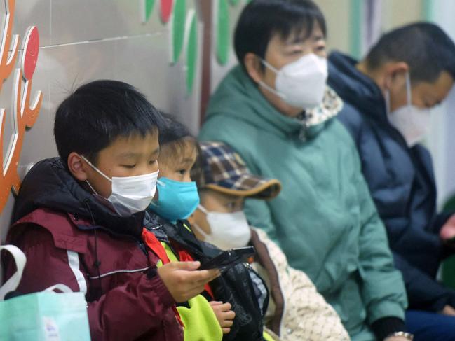 Masked children, accompanied by adults, wait to be seen by medical staff at the pediatric department of a hospital in Hangzhou, eastern China's Zhejiang province, on January 6, 2025. Beijing has acknowledged a surge in cases of the flu-like human metapneumovirus (HMPV), especially among children, and attributed this to a seasonal spike. (Photo by AFP) / China OUT