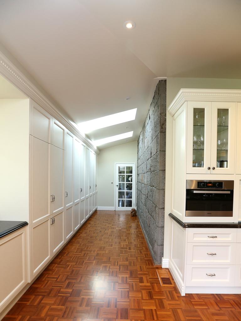 An open-plan kitchen, dining and living zone features a fireplace and window that frames views of the garden and floods the room with natural light. Picture: Andy Rogers