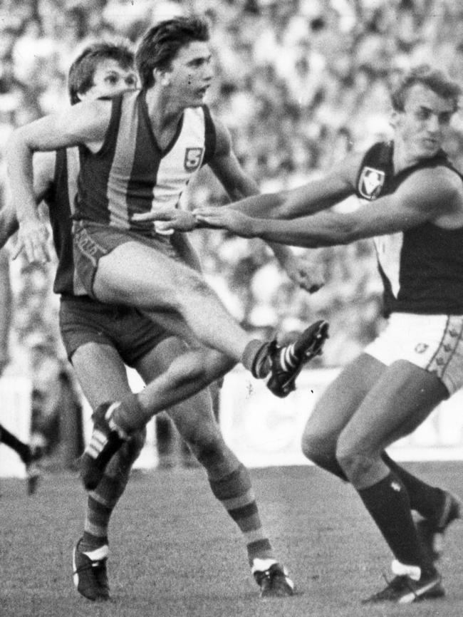 Mark Naley gets his kick away under pressure from Victoria’s Bruce Nankervis in the state game at Football Park in 1982.