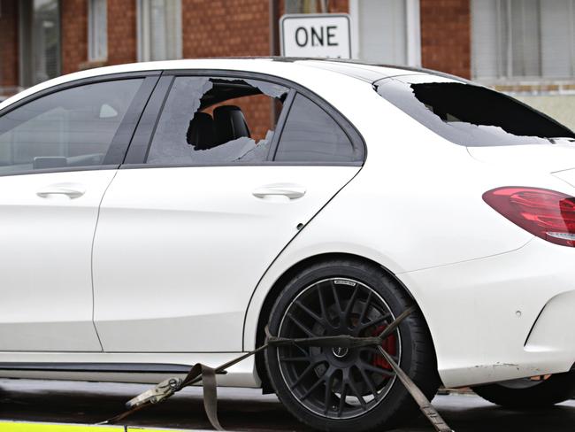 A car with bullet holes and broken windows being taken away from the crime scene. Picture: Adam Yip