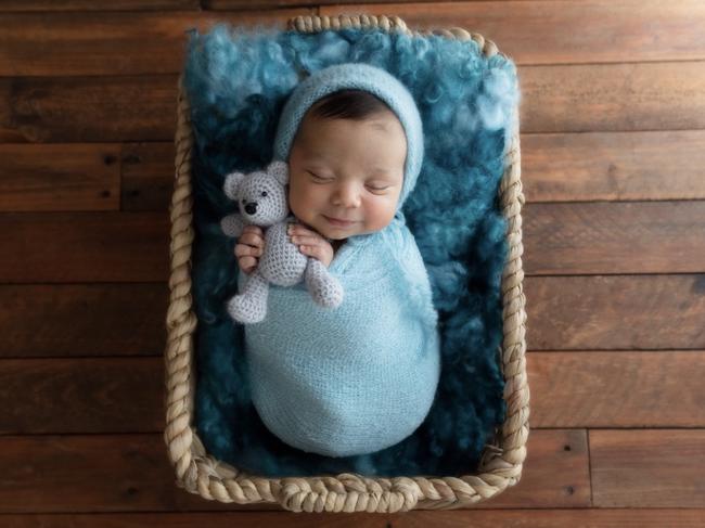 Finn Curtis at two weeks old wrapped up in a blue blanket with his favourite teddy bear. Picture: Little Cherub Photography