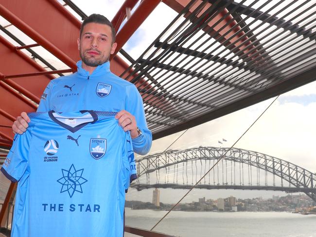 New Sydney FC player Kosta Barbarouses holds a team jersey after a media conference at the Sydney Opera House, Friday, June 7, 2019. (AAP Image/David Gray) NO ARCHIVING