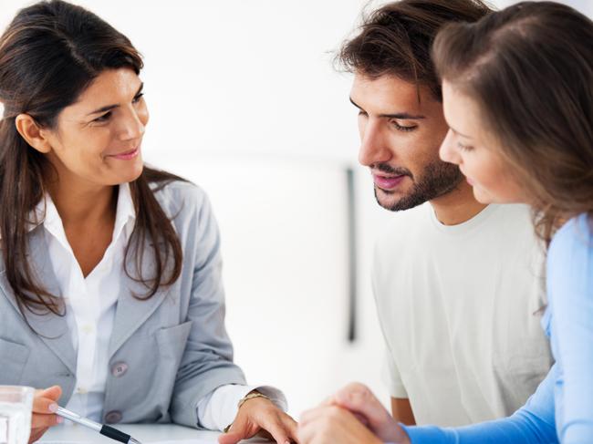 A young couple talking to a mortgage broker about the cost of their home loan. Picture: iStock.