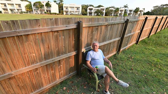 Battle over … villa owner Chris Shannon sits beside the controversial fence built by resort owner, billionaire Clive Palmer. Picture: Lyndon Mechielsen