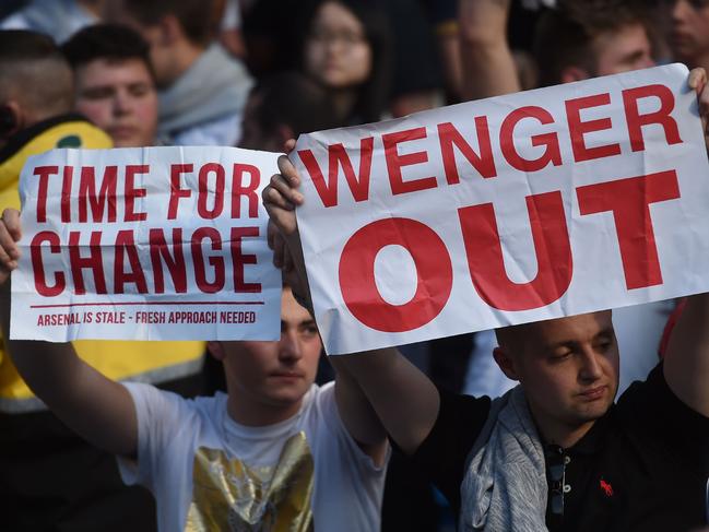 Arsenal fans hold up signs calling for the resignation of Arsenal's French manager Arsene Wenger after the English Premier League football match between Manchester City and Arsenal at the Etihad Stadium in Manchester, north west England, on May 8, 2016. / AFP PHOTO / PAUL ELLIS / RESTRICTED TO EDITORIAL USE. No use with unauthorized audio, video, data, fixture lists, club/league logos or 'live' services. Online in-match use limited to 75 images, no video emulation. No use in betting, games or single club/league/player publications. /