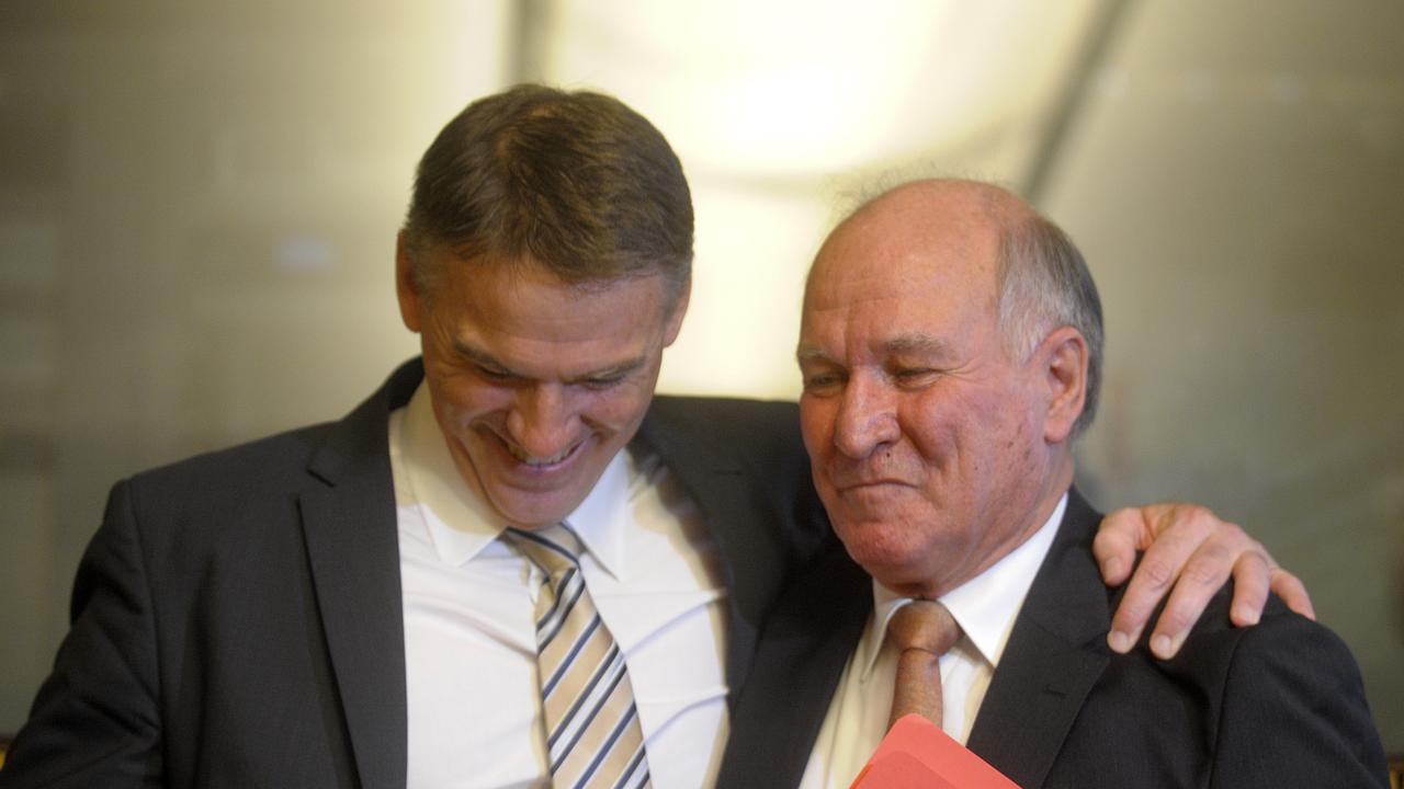 Independent MP Rob Oakeshott (left) hugs fellow independent Tony Windsor. (AAP Image/Alan Porritt) NO ARCHIVING