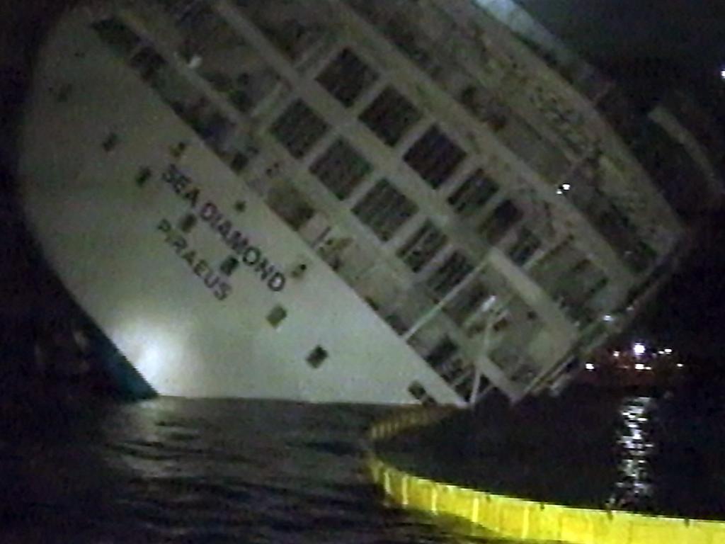 The Greek cruise ship 'Sea Diamond' flanked by anti-pollution netting and heavily listing, shortly before it sank off the Aegean island of Santorini on April 6, 2007. Picture: ALPHA TV / AFP