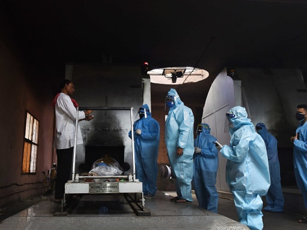 NEW DELHI, INDIA - MAY 21: Relatives of a Covid-19 victim in PPE coveralls perform the last rites at Nigambodh Ghat crematorium, on May 21, 2021 in New Delhi, India. (Photo by Ajay Aggarwal/Hindustan Times via Getty Images)