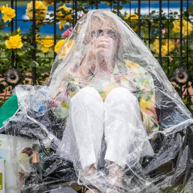 A woman prepares for the rain with a poncho tent. Picture: Jake Nowakowski