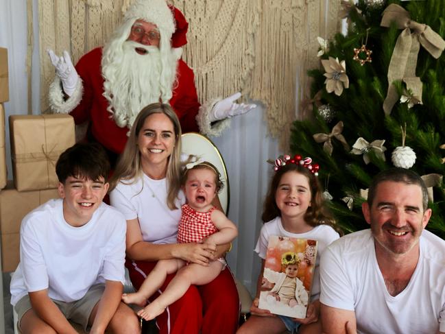 The family holds up a picture of Lola in this year's Santa photo. Picture: Supplied