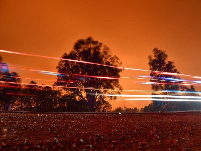 Light streaks from passing vehicles are pictured as the afternoon sky glows orange from bushfires in the area around the town of Nowra in the Australian state of New South Wales on December 31, 2019. - Thousands of holidaymakers and locals were forced to flee to beaches in fire-ravaged southeast Australia on December 31, as blazes ripped through popular tourist areas leaving no escape by land. Picture: Saeed Khan/AFP