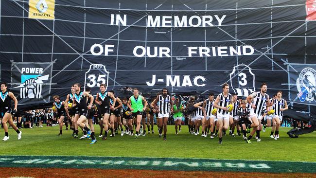 Power and Collingwood players run through a joint banner to honour McCarthy in 2013.