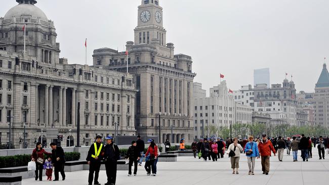 Tourists walk along the historical buildings of the Bund in Shanghai, China.